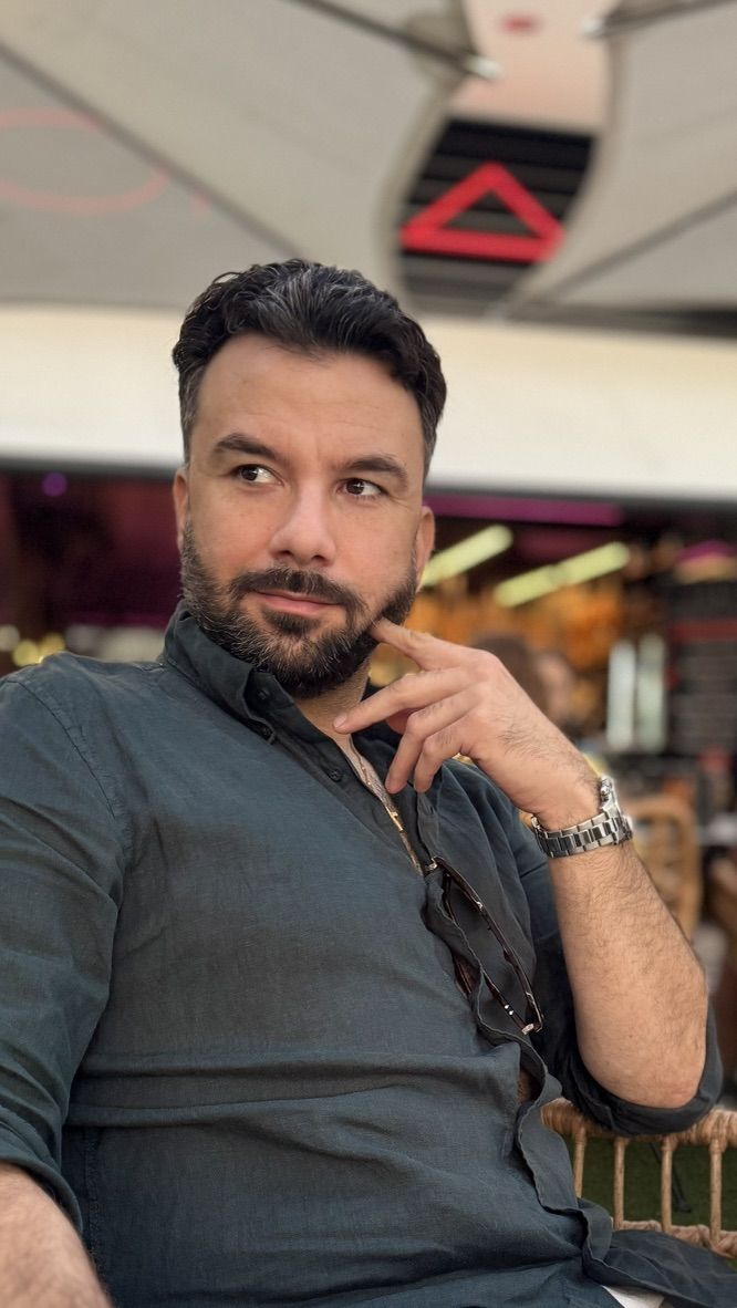 Eftim Paskalev sentado en una terraza, con camisa verde oscuro y la mano en la barbilla